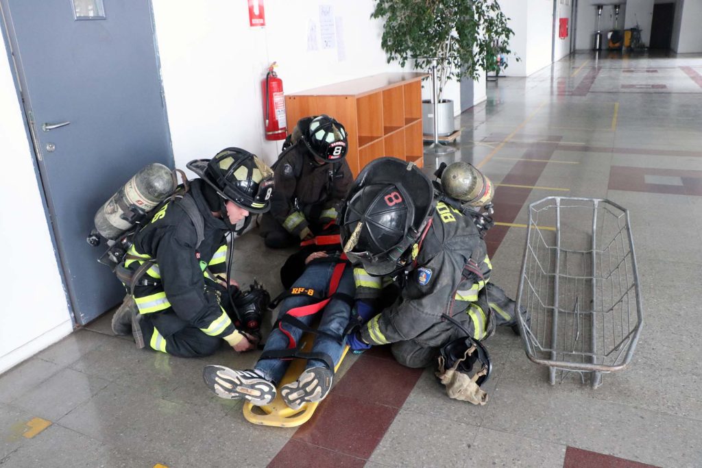 Bomberos de la Octava compañía de Peñalolén asiste a persona que simula estar lesionado durante simulacro en el Instituto Profesional ARCOS.